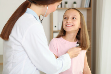 Obraz na płótnie Canvas Young girl doctor pediatrician makes a checkup to a little girl