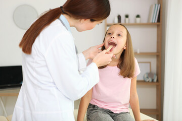 Young girl doctor pediatrician makes a checkup to a little girl