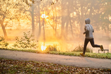 Man running in the park during autumn fall sunny morning