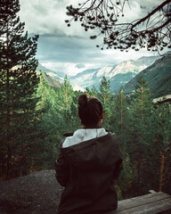 girl sitting on a rock against the background of mountains and clouds