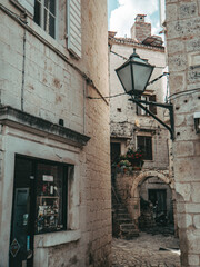 wooden shuttered windows and old lamp light in the streets of trogir with blue sky and clouds	