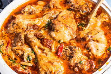 Cooking Tuscan chicken with sun-dried tomatoes, tomato paste, spinach, cream and cheese in a pan.