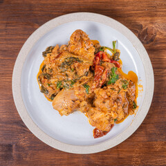 Ready Italian dish - Tuscan chicken with dried tomato and cream sauce with cheese and onions on a plate on a wooden table, top view, close-up