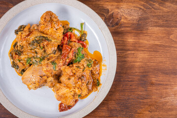 Ready Italian dish - Tuscan chicken with dried tomato and cream sauce with cheese and onions on a plate on a wooden table, top view, close-up, copy space