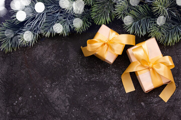 Fototapeta na wymiar Beautiful Christmas gifts with a gold bow and a fir branch on a dark black background. Flat design. Copy space.
