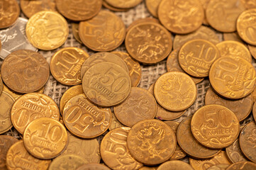 Old coins are scattered on rough sacking. Close up. Background image.