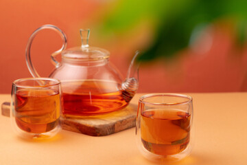 Glass teapot and two glass cups with tea