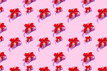 Seamless regular pattern with boxes of gifts on a pink background. Hard light. New Years, Christmas and birthday concept.