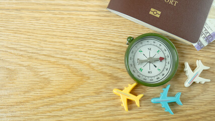 The passport and compass on wood table for travel content.