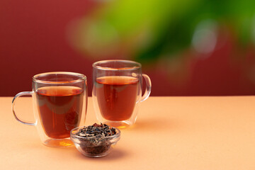 Two glass cups of black tea on beige table