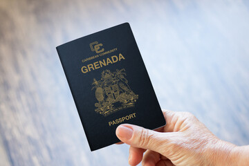 hand holding grenada passport with wooden background - obrazy, fototapety, plakaty