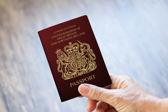 Hand Holding UK Passport With Wooden Background