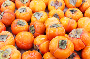 Ripe orange persimmons. on the table in the market. A bunch of organic persimmon fruits at a local farmers market. Persimmon background. Flat lay. Copy space for text and content.