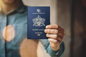 Man wearing blue jeans shirt and showing saint Lucia passport. Blurred background. Horizontal mockup - obrazy, fototapety, plakaty