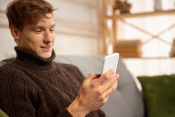 Man reading message, greetings for New Year and Christmas 2021 from friends or family with his cellphone. Getting in touch using devices. Holidays, celebration. Looks cheerful, happy, careful.