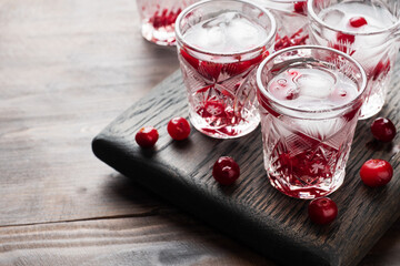 Stacks of vodka and cranberries on a wooden stand and background. Copy of the space. Bar alcoholic beverage tincture.