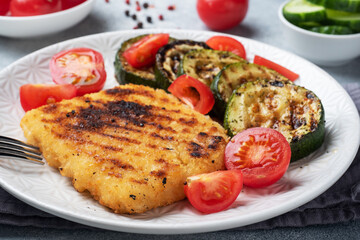 Schnitzel of chicken and zucchini cooked on the grill. Fresh tomatoes on a plate. Ready delicious dinner lunch.