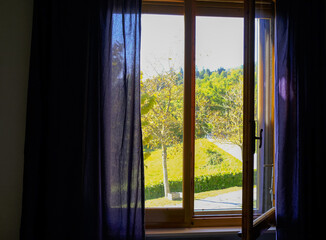 Autumn view from the wooden window with blue curtains. Home interior. Window design
