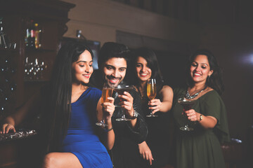 Asian Indian young friends at lounge bar having drinks, celebrating success or new year or birth day