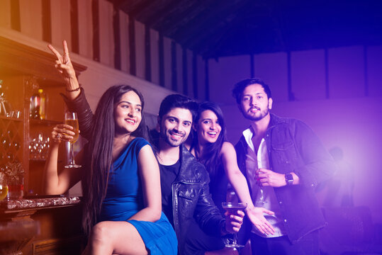 Asian Indian young friends at lounge bar having drinks, celebrating success or new year or birth day
