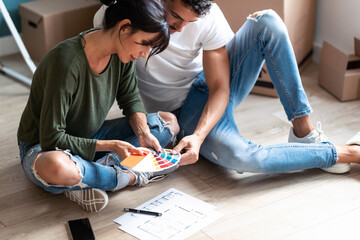 Young attractive couple choosing colors in a color palette to paint the walls of the apartment...