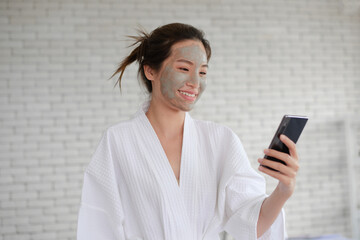 Fototapeta premium lady use smartphone while wating for clay mask cleasing on her face