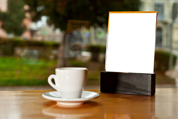 Obraz na płótnie Canvas Tablet with white place for text on a wooden board. Coffee near the stand on the table. Mockup for design. Copy space for advertising.