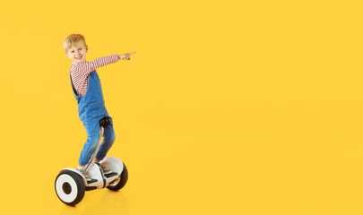 Funny child boy boy riding on hoverboard or gyroscooter on yellow background. Advertising...
