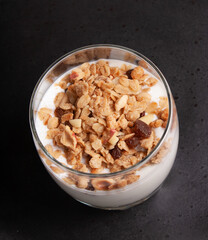 Healthy breakfast. Yogurt with granola, nuts, fruits. On a black background.