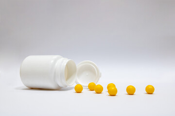 Round vitamin C pills scattered near the box