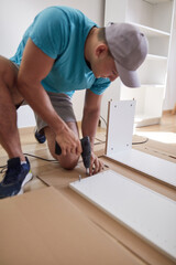 Handyman worker assembling furniture in new apartment, moving in and being hardworking.