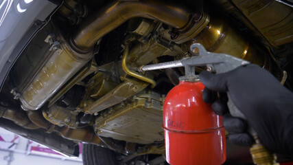 A man in a car service blows out the lower part of the car body. Protective coating of the lower part of the car body.