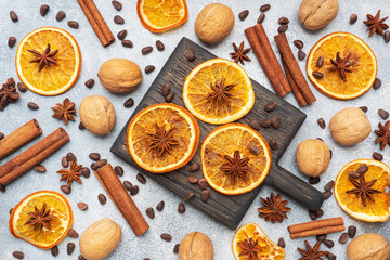 Christmas composition with dried oranges, cinnamon, anise and nuts on a gray concrete background. Flat lay top view.