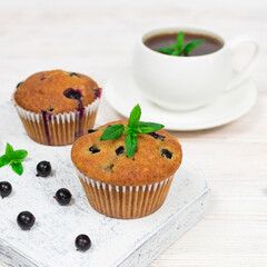 Cupcakes with black currant and mint leaves on a white plate. Close-up. Selective focus.