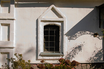 White stucco wall of an old house with a window and a shadow from the porch
