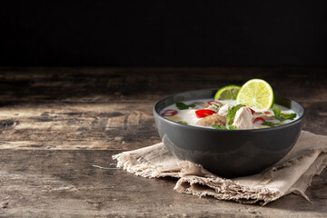 Traditional Thai food Tom Kha Gai in bowl on wooden table. Copy space