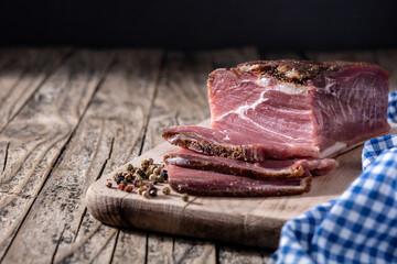 Dried and smoked meat on wooden table.	