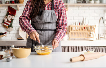 Young latin woman whisking eggs cooking at the kitchen