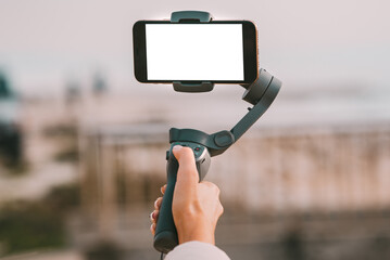Woman hand with a gimbal for smartphone with blank screen. Vlog and video blogging concept. © Creative Cat Studio