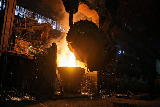 A stream of hot metal pours into the ladle. Electric arc furnace shop EAF. Metallurgy.