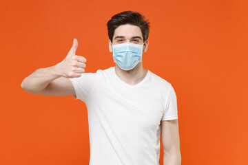 Cheerful young man wearing casual white t-shirt sterile face mask to safe from coronavirus virus...
