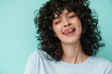 Joyful beautiful curly girl winking and showing her tongue