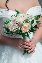 Beautiful wedding bouquet in hands of the bride in white dress