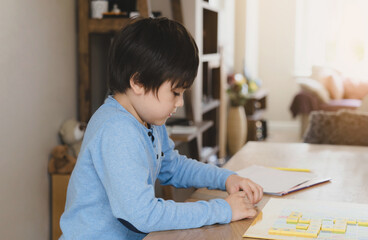 Naklejka premium Preschool kid learning English words game,Child boy concentrated with spelling English letter with parent at home. Distance Education, Activity for children for home schooling, New normal lifestyle