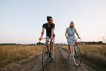 Lovers riding bikes in the nature at dusk
