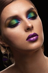 portrait of a beautiful girl with bright skillful make-up with large earrings on a black background