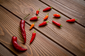 Pods of red and yellow chili peppers lying on a dark wooden surface. Background for spices and...