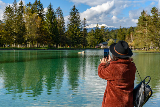 Stylish girl talking a picture of the lake in autumn