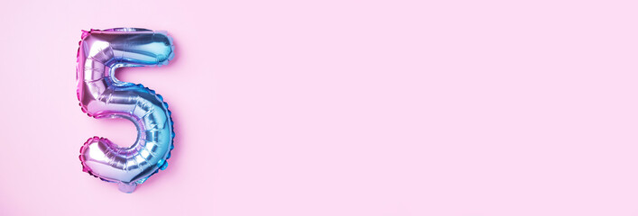 Creative layout. Rainbow foil balloon number and digit five 5. Birthday greeting card. Anniversary concept. Top view. Copy space. Stylish colored numeral over pink background. Numerical digit.