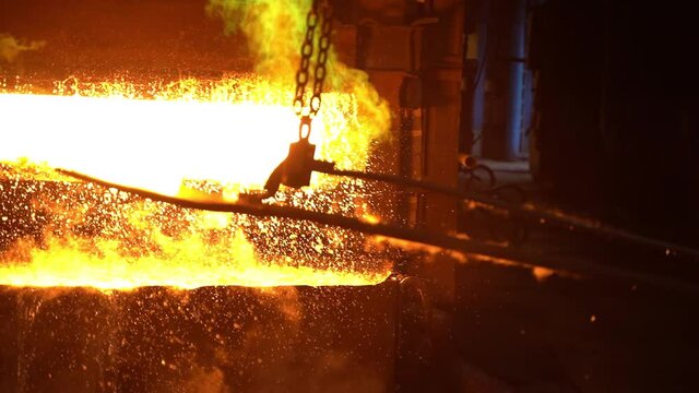 From the blast furnace, the Metallurgist takes out a hot metal billet with tongs.